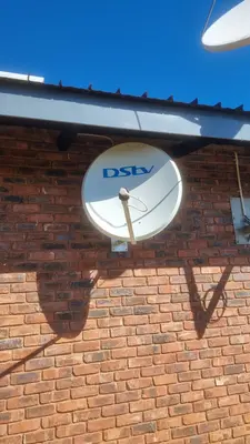 DStv dish bracket-mounted on a brick wall and angled for signal