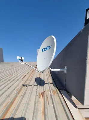DStv dish on a metal roof against a clear blue sky