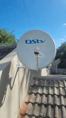 Wall-mounted satellite dish on a suburban house, angled east for signal