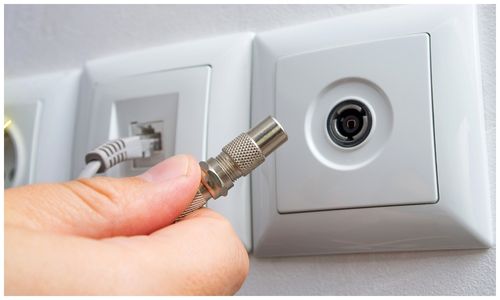 A coaxial cable being plugged into a TV wall point